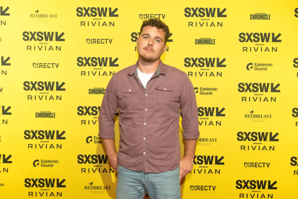 Filmmaker Mitchell Cole at the SXSW step-and-repeat for It Ends, photographed against the festival backdrop. Photo by Daniel Poe.